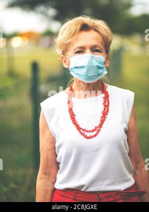 Porträt einer schönen Blondine Frau trägt eine Maske. Menschen zu Fuß Hunde, während Covid-19 Pandemie, im Freien. Stockfoto