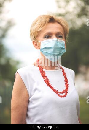Porträt einer schönen Blondine Frau trägt eine Maske. Menschen zu Fuß Hunde, während Covid-19 Pandemie, im Freien. Stockfoto