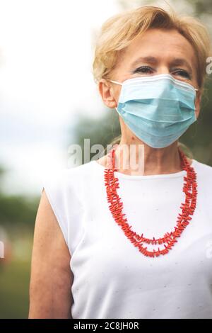Porträt einer schönen Blondine Frau trägt eine Maske. Menschen zu Fuß Hunde, während Covid-19 Pandemie, im Freien. Stockfoto