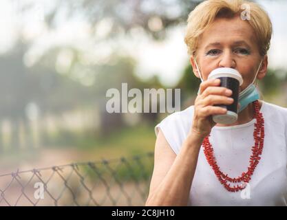 Porträt einer schönen Blondine Frau trägt eine Maske. Menschen zu Fuß Hunde, während Covid-19 Pandemie, im Freien. Stockfoto