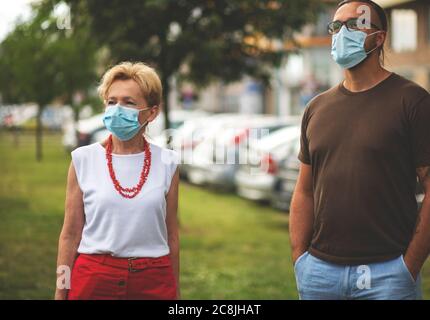 Porträt einer schönen Blondine Frau trägt eine Maske. Menschen zu Fuß Hunde, während Covid-19 Pandemie, im Freien. Stockfoto