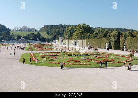 Touristen wandern im regulären Park vor dem Schloss Schönbrunn. Schloss Schönbrunn und Gärten sind UNESCO-Weltkulturerbe Stockfoto