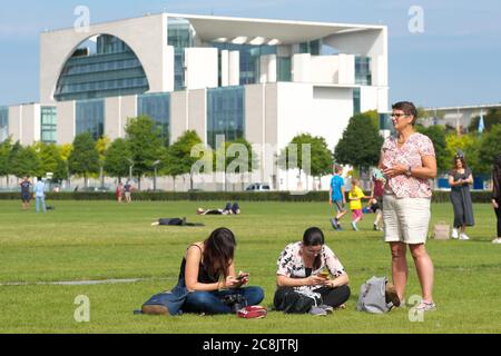 Berlin Deutschland Besucher auf dem Rasen vor dem modernen Kanzleramt Gebäude der Mitte der Bundesregierung Stockfoto