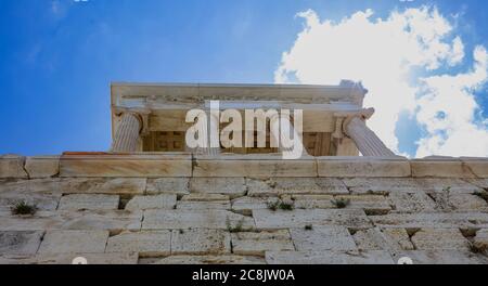 Athen Akropolis, Wahrzeichen Griechenlands. Der Tempel der Athena Nike Low-Angle-Ansicht am Propylaea Tor Eingang, blau bewölkten Himmel in einem Frühjahr sonnigen Tag. Stockfoto