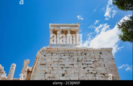 Athen Akropolis, Wahrzeichen Griechenlands. Der Tempel der Athena Nike Low-Angle-Ansicht am Propylaea Tor Eingang, blau bewölkten Himmel in einem Frühjahr sonnigen Tag. Stockfoto