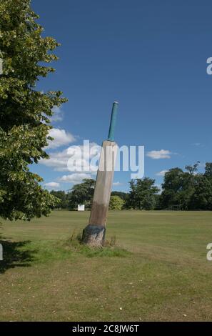 Cricket bat geschnitzt aus dem Baumstumpf mit einem hellen blauen Himmel Hintergrund auf dem Rand eines Dorfes Cricket Ground in Rural Devon, England, Großbritannien Stockfoto