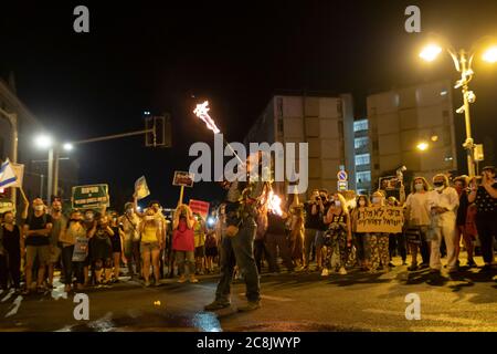 Der Protestler spuckte Feuer, als Tausende Demonstranten vor dem offiziellen Wohnsitz von Premierminister Benjamin Netanjahu in Jerusalem massierten und seinen Rücktritt wegen seiner Korruptionsvorwürfe und wegen der Misswirtschaft der Krise des Coronavirus forderten und der Demokratie in Jerusalem, Israel, schadet. Stockfoto