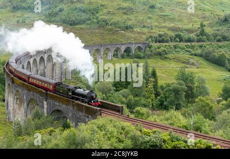 JACOBITE DAMPFZUG WEST HIGHLAND LINIE SCHOTTLAND IM SOMMER ZUG UND WOLKE VON WEISSEM RAUCH AUS DEM TRICHTER, WIE ES DAS ENDE DES GLENFINNAN VIADUKT ÜBERQUERT Stockfoto