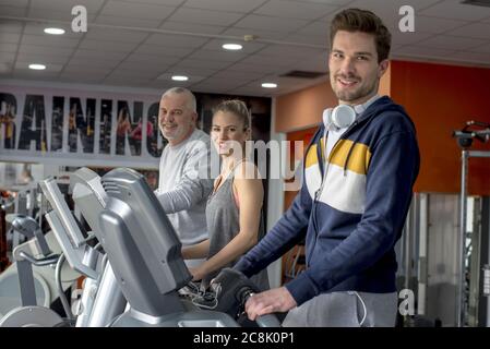 Gruppe lächelnder Leute, die zusammen auf den Laufbändern im trainieren Fitnessraum Stockfoto