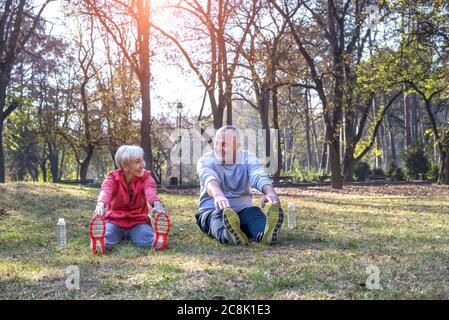 Aktives kaukasisches Seniorenpaar trägt Sportkleidung und trainiert in einem Park An einem sonnigen Tag Stockfoto