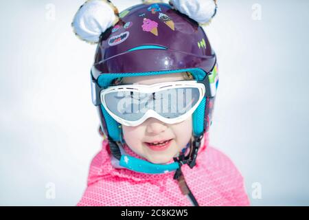 Portrait von niedlichen glücklich Skifahrer Mädchen in Helm und Brille in einem Winter-Skigebiet Stockfoto