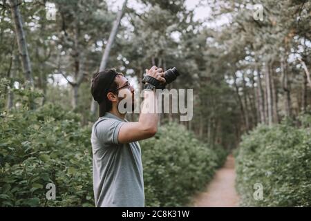 Ein junger Tourist fotografiert mit einer Kamera in einem Wald. Tourismus Stockfoto