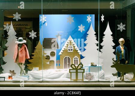 Dekoration einer Weihnachts-Schaufenster für die Marke Dolce Gabbana, Kleidungsmodelle vor dem Hintergrund von Figuren von Weihnachtsbäumen und Häusern aus Stockfoto