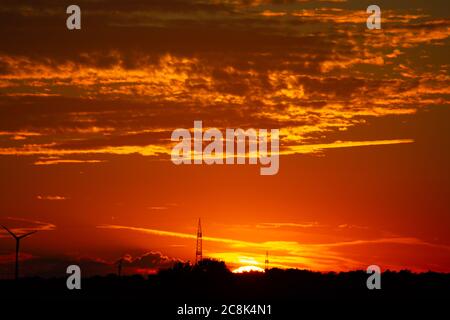 Sonnenaufgang mit Silhouetten von Windkraftanlagen am Horizont Stockfoto