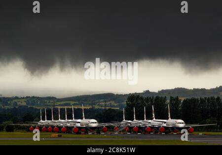 Glasgow, Schottland, Großbritannien. 23. Juli 2020. Im Bild: Unter einer drohenden dunklen, stürmischen Wolke sitzen die geerdeten Flugzeuge des Typs British Airways (BA) Airbus A319/A320/A321 auf der zweiten Landebahn des Flughafens Glasgow und warten darauf, verkauft oder gelagert zu werden. Seit März sitzen diese Flugzeuge auf dem Asphalt der Flughäfen untätig, was der weltweiten Krise des Coronavirus (COVID19) zusteht. British Airways hat fast 12,000 Mitarbeiter gekürzt und bis heute ihre gesamte Boeing 747-Flotte in den Ruhestand, um die Betriebskosten zu senken. Quelle: Colin Fisher/Alamy Live News. Stockfoto