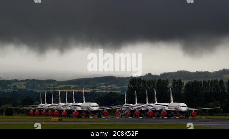 Glasgow, Schottland, Großbritannien. 23. Juli 2020. Im Bild: Unter einer drohenden dunklen, stürmischen Wolke sitzen die geerdeten Flugzeuge des Typs British Airways (BA) Airbus A319/A320/A321 auf der zweiten Landebahn des Flughafens Glasgow und warten darauf, verkauft oder gelagert zu werden. Seit März sitzen diese Flugzeuge auf dem Asphalt der Flughäfen untätig, was der weltweiten Krise des Coronavirus (COVID19) zusteht. British Airways hat fast 12,000 Mitarbeiter gekürzt und bis heute ihre gesamte Boeing 747-Flotte in den Ruhestand, um die Betriebskosten zu senken. Quelle: Colin Fisher/Alamy Live News. Stockfoto