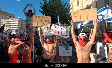 Junge israelische Demonstranten halten Plakate hoch, als etwa tausend Demonstranten vor dem offiziellen Wohnsitz von Ministerpräsident Benjamin Netanjahu in Jerusalem massierten und seinen Rücktritt wegen seiner Korruptionsvorwürfe und der so bezeichnete Misswirtschaft der Krise des Coronavirus forderten und der Demokratie in Jerusalem, Israel, schadet. Stockfoto