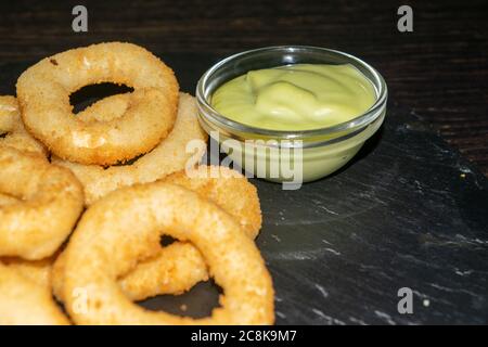 Zwiebelringe und ein Glas-Topf mit Sauce. Nahaufnahme Stockfoto