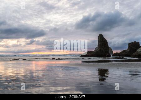 Ende des Tages am Strand ein bisschen Farbe in den dunklen Wolken und die prominenten Felsen kennzeichnet charakteristischen Face Rock State Park, Bandon Oregon Stockfoto