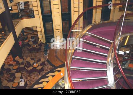 Lustiger Urlaub auf einem Kreuzfahrtschiff mit Blick auf die Wendeltreppe in der Hauptatrium-Lobby. Stockfoto