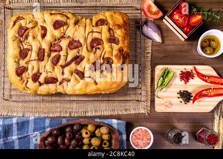 Traditionelle italienische Focaccia mit Pfefferoni, Kirschtomaten, schwarzen Oliven, Rosmarin ando Zwiebel - hausgemachte Fladenbrot Focaccia. Stockfoto