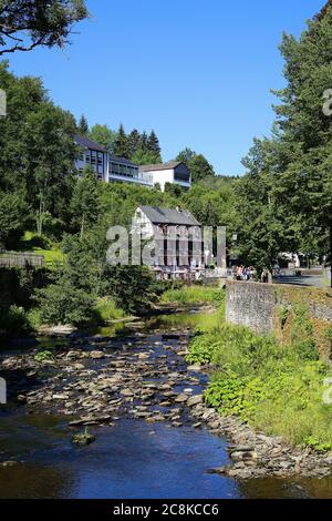 Monschau, Deutschland (Eifel) - 9. Juli. 2020: Blick über den Fluss auf Holzrahmen Denkmal Haus und Restaurant Stockfoto