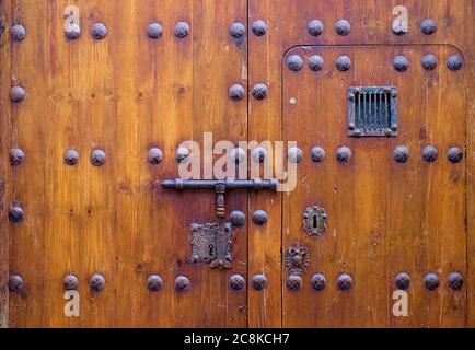 Versperrte alte dekorative Holztür mit einem kleinen, piependen Fenster. Stockfoto