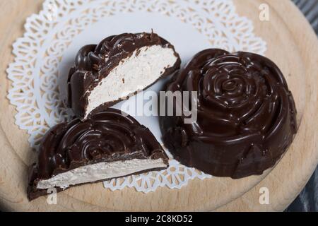 Auf einer weißen Serviette liegt ein in der Form einer Rose gemachtes Schokoladen-Marshmallow. Eine Marshmallow wird halbiert, eine Scheibe ist sichtbar. Stockfoto