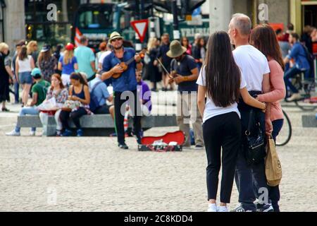 Amsterdam, Niederlande. Juli 15, 2016. Eine Familie umarmt sich an einem Sommertag auf einem Amsterdamer Platz voller Menschen, Straßenmusikanten und Künstler Stockfoto