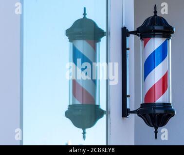 Drehzylinder eines Friseursalons und seine Spiegelung im Glas eines Fensters Stockfoto