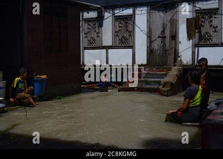 Dhaka, Bangladesch. Juli 2020. Eine von Hochwasser betroffene Familie steht vor ihrem überfluteten Haus.die Hochwassersituation in Munshiganj verschlechtert sich. Durch den starken Regen ist der Wasserstand des Padma-Flusses gestiegen, was zu einer Überschwemmung führte. Mindestens 1.5 Millionen Menschen sind betroffen, Häuser und Straßen in Dörfern überschwemmt. Beamte des Hochwasserprognosen- und Warnzentrums (FFWC) haben berichtet, dass die Überschwemmungssituation in 15 nördlichen und zentralen Bezirken durch den Anstieg des Wasserstials der Hauptflüsse verursacht wurde. Kredit: SOPA Images Limited/Alamy Live Nachrichten Stockfoto