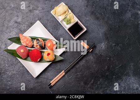 Sushi-Brötchen aus Reis, geräuchertem Aal, Frischkäse und fliegender Fischrohe Set heiße Brötchen mit Avacado, Lachs, Frischkäse, Algen, Sojasauce, Ingwer auf Stockfoto