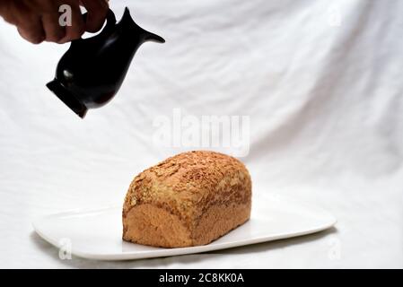 Schwarzes Glas und Brot auf weißem Stoffhintergrund. Stockfoto