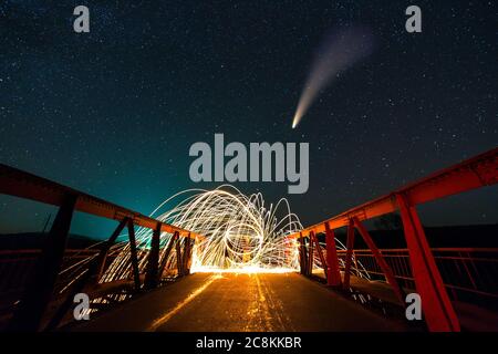 Lange Exposition von spinnenden Stahlwolle in abstraktem Kreis machen Feuerwerk Duschen von gelb glühenden Funken auf einer Brücke mit dunklen Nacht Sternenhimmel darüber. Stockfoto