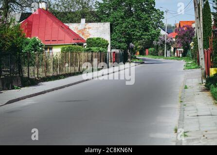 Asphaltstraße durch Dorf neben Zäunen und Häusern Stockfoto