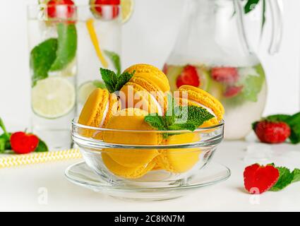 Gelbe Makronen in einer Glasschale auf weißem Hintergrund. Französisches Dessertkonzept Stockfoto