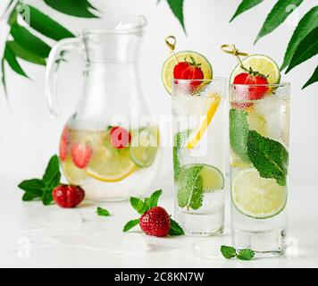 Erfrischendes Wasser mit Limette, Zitrone, Minze und Erdbeere auf weißem Hintergrund. Stockfoto