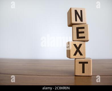 Konzept Wort "next" auf Würfel auf einem schönen Holztisch. Weißer Hintergrund. Geschäftskonzept. Speicherplatz kopieren. Stockfoto