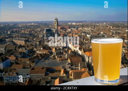 Ein Glas helles belgisches Bier mit Panoramablick von oben auf die Altstadt und die große Kathedrale in Gent, Belgien. Blick von oben auf Gent, Belgien Stockfoto