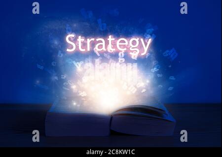 Offenes Buch mit Strategie-Inschrift. Licht kommt aus dem offenen Buch mit Wortstrategie. Stockfoto