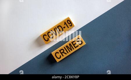 'Covid-19 Crimes' Worte auf Holzblöcken. Geschäftskonzept. Schöner weißer und blauer Hintergrund. Stockfoto