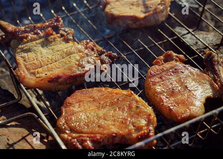 Gegrillte Schweinesteaks lagen über Kohlen auf einem Grill Stockfoto