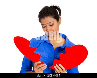 Porträt einer jungen traurigen, depressiven, verwirrt Frau, hält gebrochenes Herz in den Händen isoliert auf weißem Hintergrund. Stockfoto