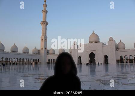 Abuda, Vereinigte Arabische Emirate. Schöne Aussicht auf die Scheich-Zayed-Moschee. Silhouette einer Frau im Nationalkleid im Vordergrund. Stockfoto