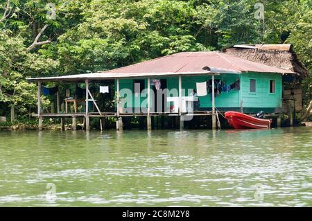 Rio Dulce, Guatemala - 13. Mai 2011: Eines der besseren Kekchi indischen Holzhäuser entlang des Rio Dulce in Guatemala. Beachten Sie das Motorboot anstelle von Th Stockfoto