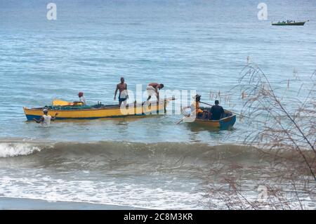 Grenada, Westindien, Karibik - 28. Dezember 2011: Männer in Fischerbooten an der Küste von Granada in der Karibik. Stockfoto