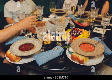 Konzentrieren Sie sich auf Hände Servieren Gerichte mit Fleisch und Gemüse an eine Gruppe von Freunden um einen Tisch auf einer Sommerterrasse versammelt. Stockfoto