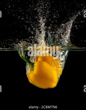 Gelbe Paprika abgeworfen und auf Wasser aufschlagen Stockfoto