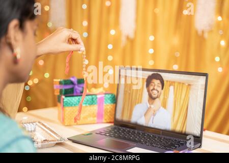 Schulteransicht des Schwester-Videos, das ihren Bruder ruft, Rakhi oder Raksha Bandhan während des Festivals zu binden und Geschenk zu zeigen, das empfangen wurde - Konzept von Far Stockfoto