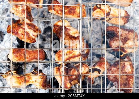 Saftige Fleischsteaks über Holzkohle auf einem Drahtgitter gekocht. Picknick in der Natur. Fleisch auf einem Feuer in der freien Luft gekocht. Blick von oben. Nahaufnahme. Stockfoto